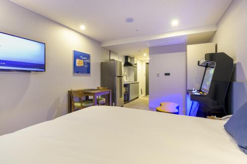 a room with a bed and a flat screen tv at Ventimo Hotel & Residence Jeju in Jeju