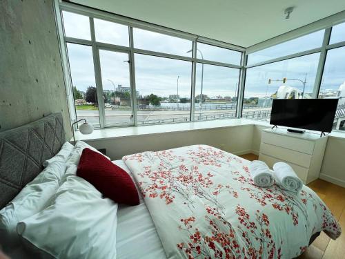 Schlafzimmer mit einem Bett, einem TV und Fenstern in der Unterkunft Janion Oasis by IRIS PROPERTIES! in Victoria