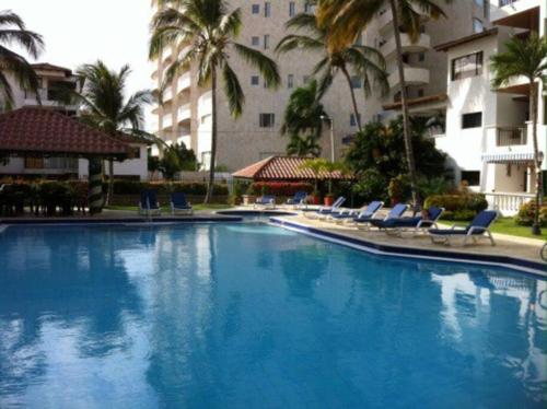 una gran piscina azul con sillas y palmeras en Edificio Arrecifes, La vida es mejor frente al mar, en Santa Marta