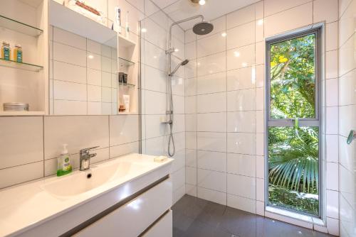 a white bathroom with a sink and a window at Inside Out House in Oneroa