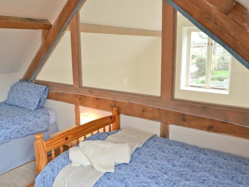 a attic room with two beds and a window at The Old Stable in West Pennard