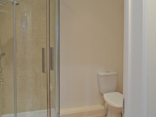 a bathroom with a toilet and a glass shower at The Old Stable in West Pennard