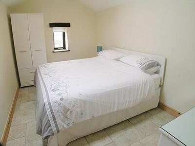 una camera con un grande letto bianco di Meadow Cottage a Westward