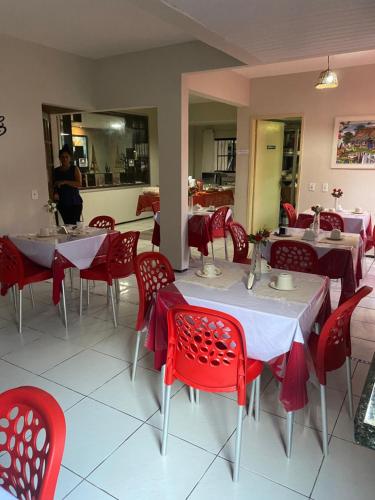 a restaurant with red chairs and tables and a person in the mirror at Nalu Beach Hotel pousada in Fortaleza