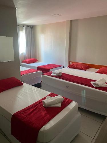 a room with four beds with red and white sheets at Nalu Beach Hotel pousada in Fortaleza