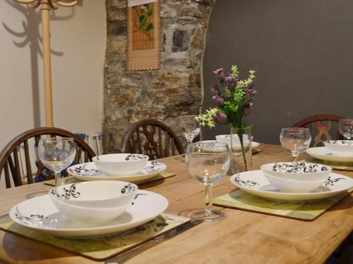 a wooden table with plates and wine glasses on it at Gareth - 19077 in Carew