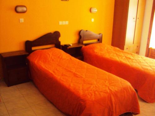 a room with two beds with orange sheets at Blue Sky in Ios Chora