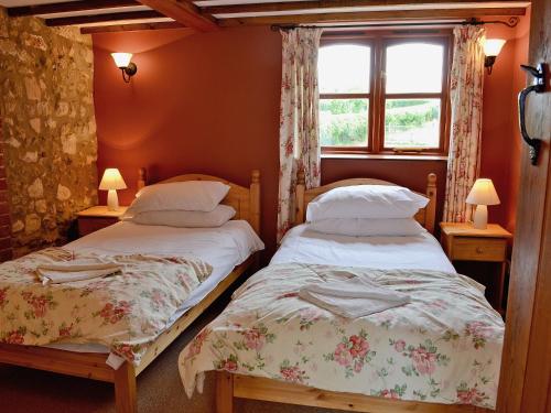 two twin beds in a room with a window at The Stables in Ansty