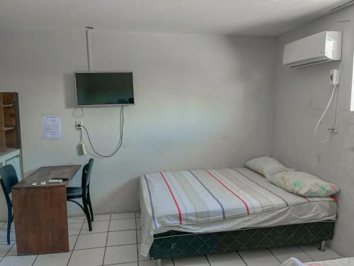 Habitación con cama, escritorio y TV. en Pousada da Praia, en Recife