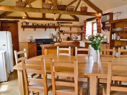 een keuken met een grote houten tafel en stoelen bij The Stables in Ansty