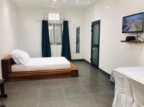 - une chambre avec un lit et une télévision à écran plat dans l'établissement Le Majestic Toamasina Hotel, à Toamasina