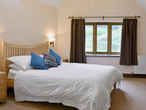 a bedroom with a large white bed with blue pillows at Stockham Lodge in Colyton