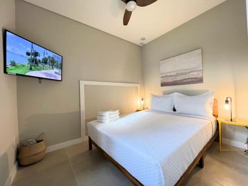 - une chambre avec un lit blanc et une télévision à écran plat dans l'établissement Apartment 2BD 1BR CalleOcho Brickell Downtow Beach 15 min A, à Miami