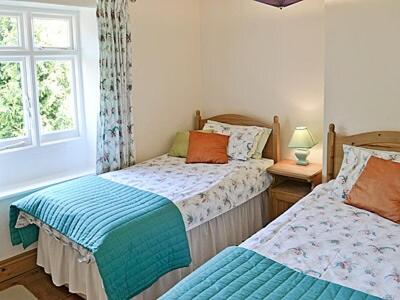 a bedroom with two beds and a window at Blacksmiths Cottages in Stiffkey