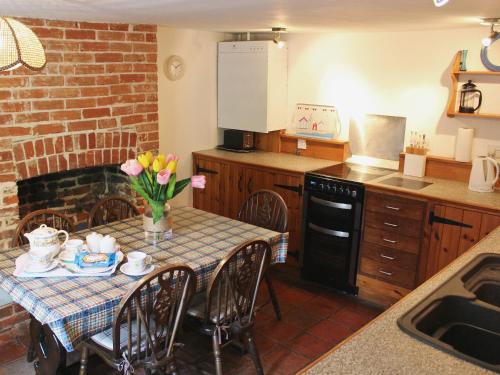 een keuken met een tafel met een vaas met bloemen erop bij Blacksmiths Cottages in Stiffkey