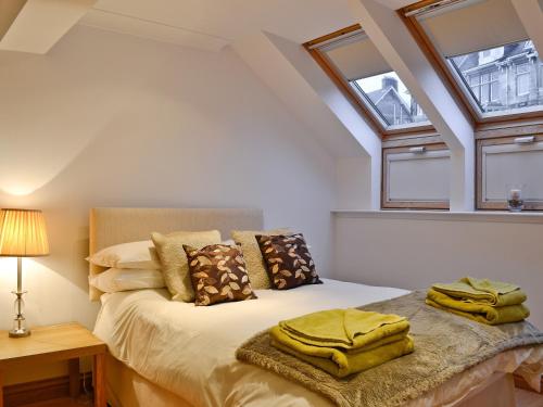 a bedroom with a bed and two windows at Bruichladdich in Rothesay