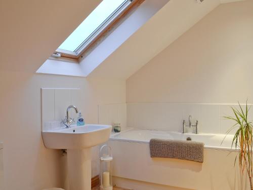 een badkamer met een wastafel, een bad en een dakraam bij Bruichladdich in Rothesay