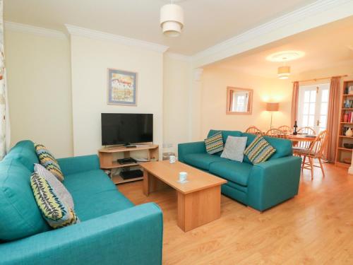 a living room with two blue couches and a television at Louisa Cottage in Weymouth