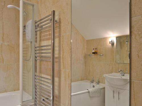 uma casa de banho com um chuveiro e um lavatório. em Rhandir Barn em Ffair-fâch