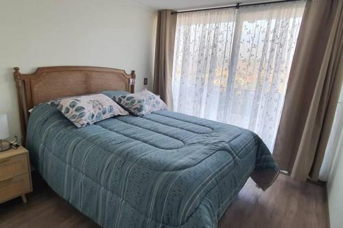 a bedroom with a bed with a blue comforter and a window at Papudo, Chile in Papudo