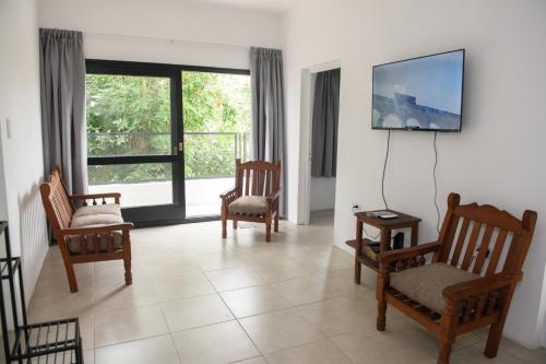 a living room with chairs and a tv on a wall at Departamento con terraza y quincho con asador in Salta