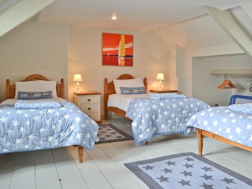 1 dormitorio con 2 camas con sábanas azules y blancas en Waters Edge en Instow