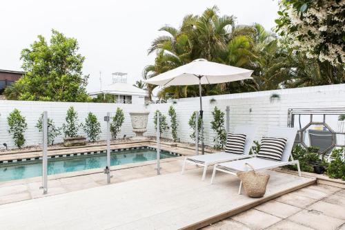 a patio with two chairs and an umbrella next to a pool at One Marola is stylish privacy in paradise in Noosa Heads