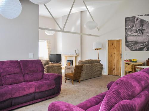 a living room with purple couches and a tv at The Mill in Goathland