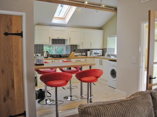 a kitchen with a table and four red bar stools at The Mill in Goathland