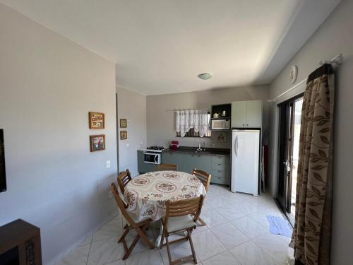 a kitchen with a table and chairs and a refrigerator at Dax Bombinhas in Bombinhas