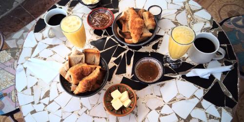 una mesa cubierta con platos de bollería y zumo de naranja en Auberge Triskell en Nuakchot