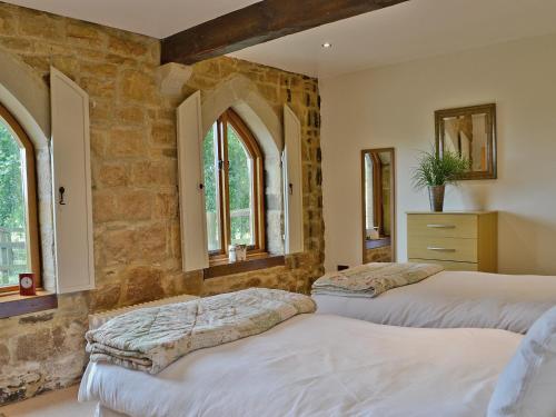 two beds in a room with stone walls and windows at The Water Castle in Wall Houses