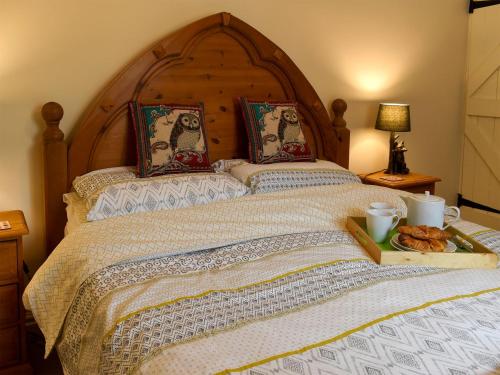 a large bed with a wooden headboard and a plate of bread at Coach House Cottage in Buckden