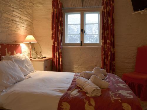 a bedroom with a bed with towels and a window at The Shooting Lodge in Saint Mabyn