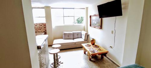 una pequeña sala de estar con sofá y TV en Bienvenidos Hospedaje, en Medellín