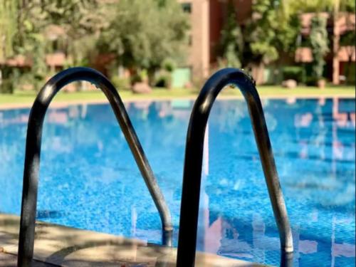 a metal railing in front of a swimming pool at Apartments Babylone 2 Marrakech in Marrakesh