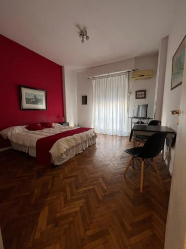 1 dormitorio con paredes rojas, 1 cama y escritorio en Departamento en Recoleta, Buenos Aires en Buenos Aires