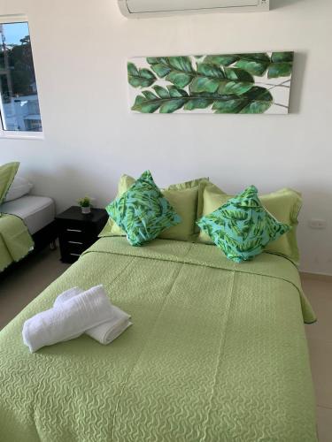 1 dormitorio con 1 cama verde y 2 toallas en Aloha Beach SAI, en San Andrés
