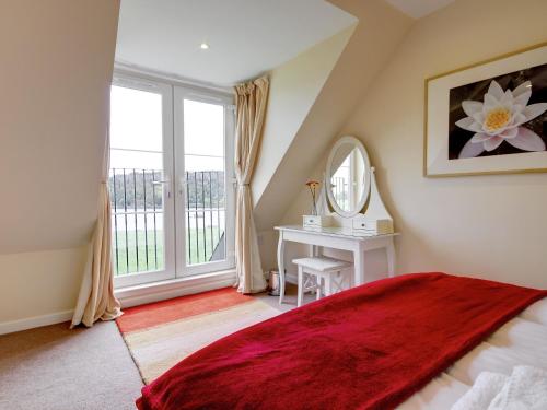 a bedroom with a bed and a window with a mirror at Peregrine Cottage in Cambusbarron