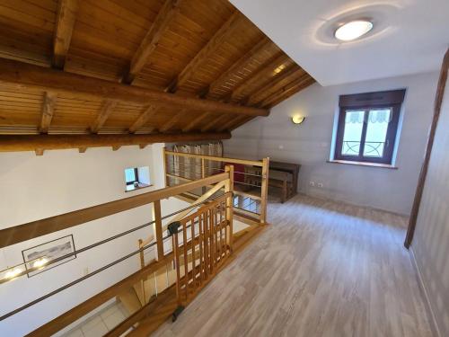 an empty room with a wooden staircase and a window at Gîte spacieux avec terrasse, confort moderne dans un cadre verdoyant et propice aux balades. - FR-1-589-79 in Bains-les-Bains