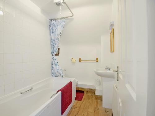a white bathroom with a tub and a sink at Fernlea in Langton Matravers