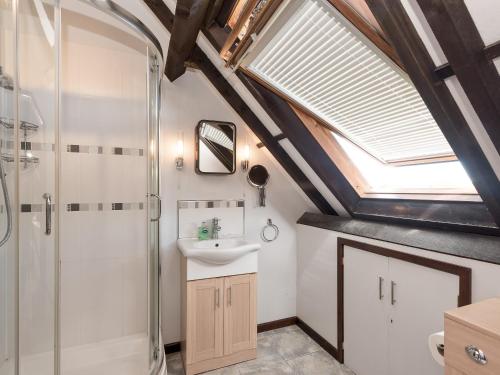 ein Badezimmer mit einer Dusche, einem Waschbecken und einem Dachfenster in der Unterkunft Sky Lark in Weybourne