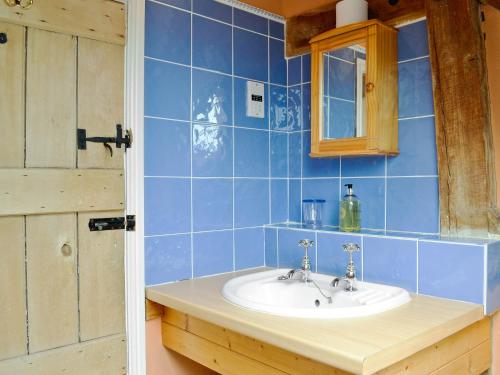 a bathroom with a sink and a blue tiled wall at The Stable-e2836 in Whitminster