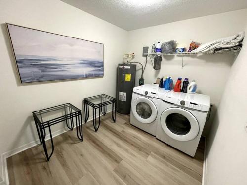 a laundry room with a washing machine and two tables at Riverside Riviera at Seminole Heights in Tampa