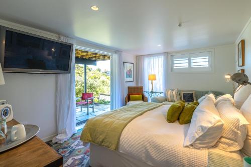 a bedroom with a large bed with a television on the wall at Relax on Newton in Oneroa