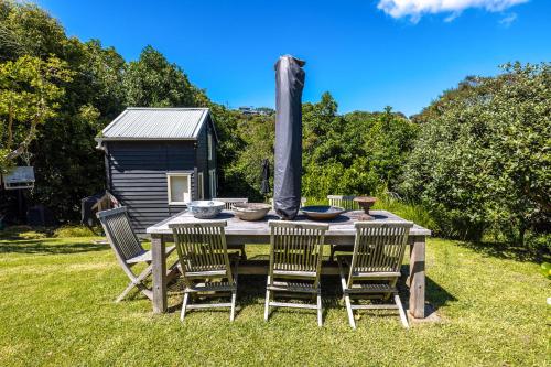 a table with four chairs and a small shed at Relax on Newton in Oneroa