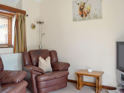 uma sala de estar com uma cadeira de couro castanho e uma televisão em Pear Tree Cottage em Gillamoor