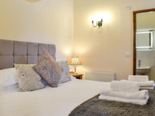 um quarto com uma cama branca e toalhas em Pear Tree Cottage em Gillamoor