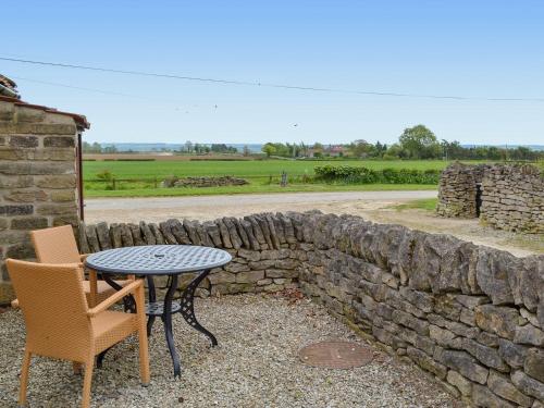 a table and chairs next to a stone wall at Pear Tree Cottage in Gillamoor