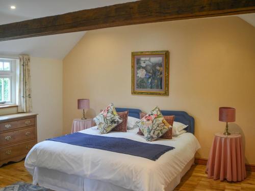 una camera da letto con letto, lenzuola e cuscini bianchi di Fiddledrill Barn a Benniworth
